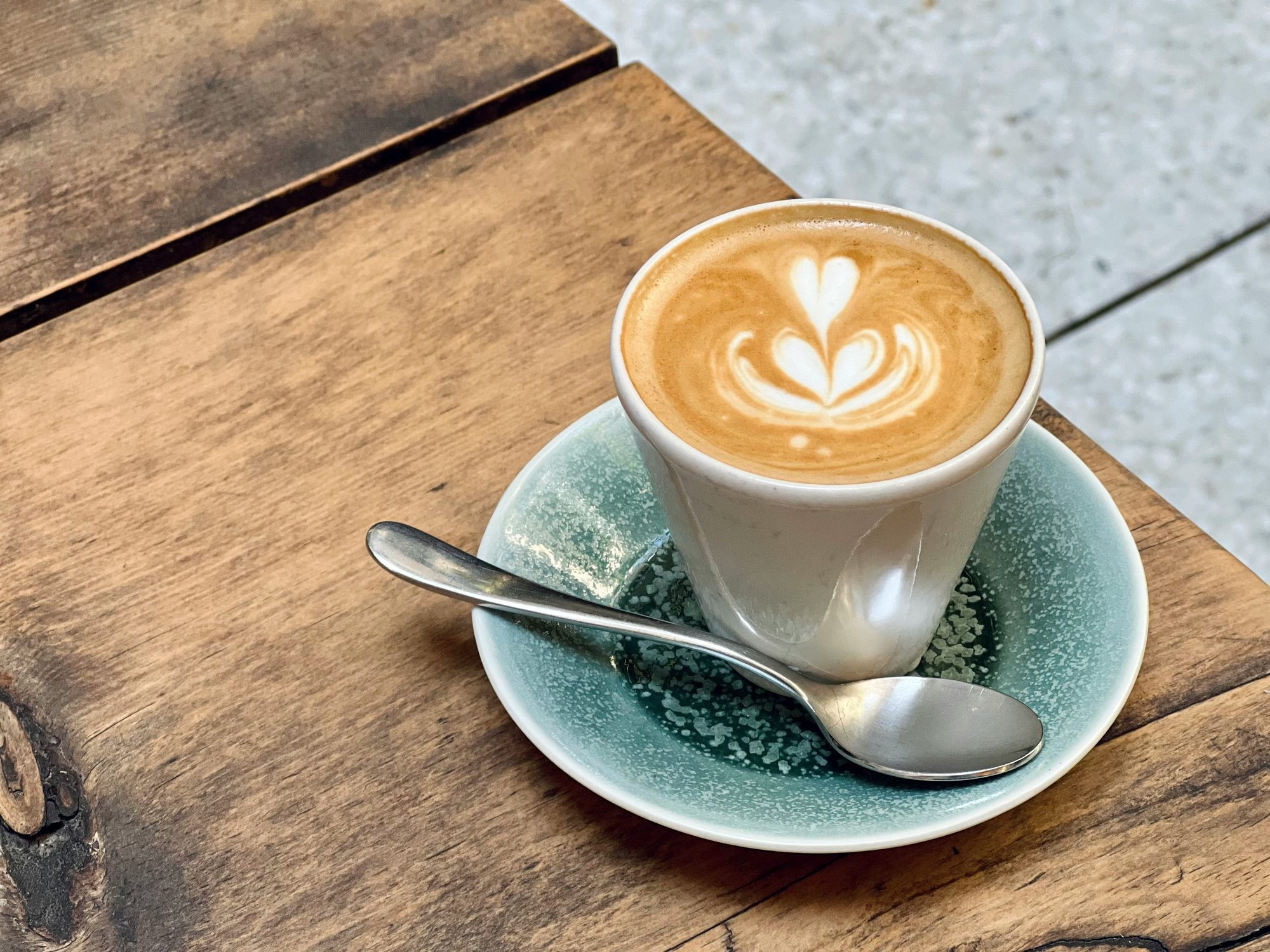 A café con leche with latte art on a wooden café table